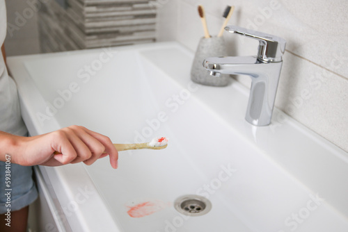 Blood on toothbrush on background of sink. Selective focus on the toothbrush.