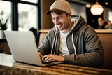 Cheerful and contented young Caucasian man sitting at desk and using laptop with a smile appears to be engaged and focused on his work. Generative AI