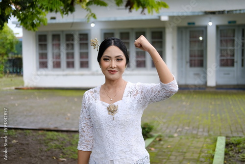 A young Indonesian woman with a happy successful expression wearing a white kebaya. Kartini's Day Concept.