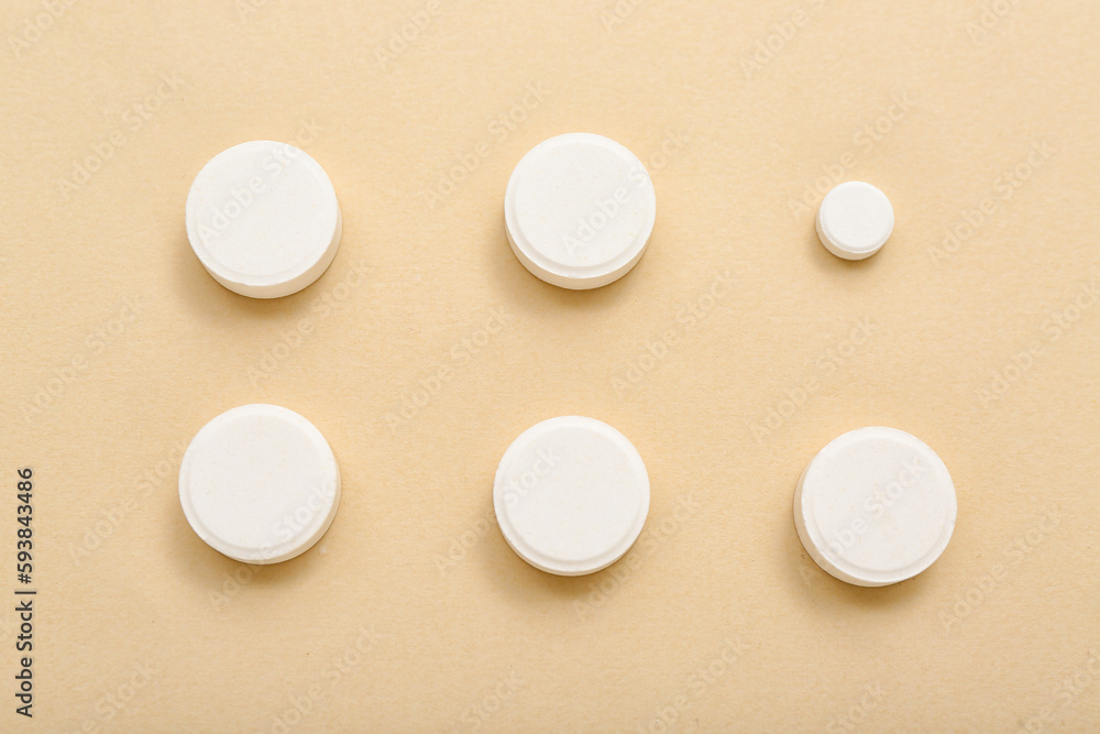 White pills on beige background White pills on beige background