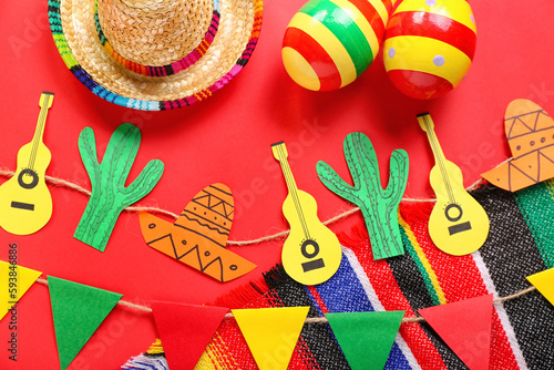 Mexican maracas with sombrero hat, paper garland and flags on red background