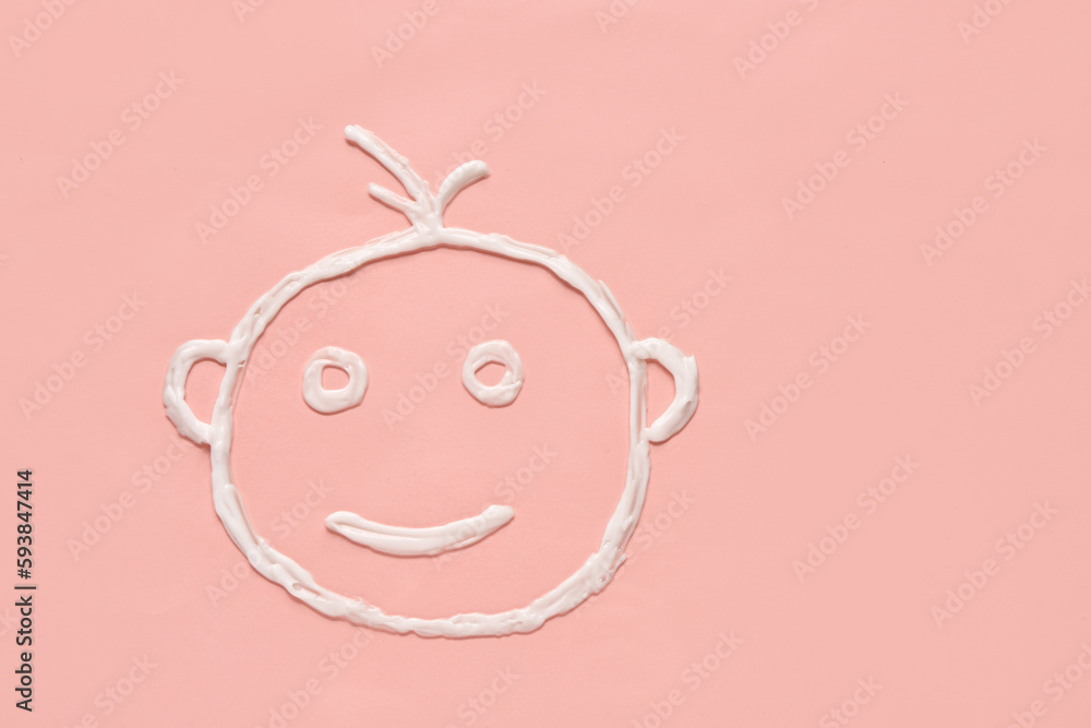 Drawing of baby face made with sunscreen cream on pink background Drawing of baby face made with sunscreen cream on pink background