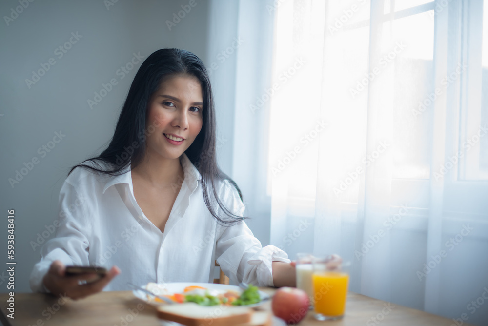 Beautiful asian woman enjoying good news on her phone with a smile on her face while looking at the camera.