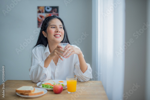 Beautiful asian girl joy with her breakfast while looking to the copy space with smile on her face.