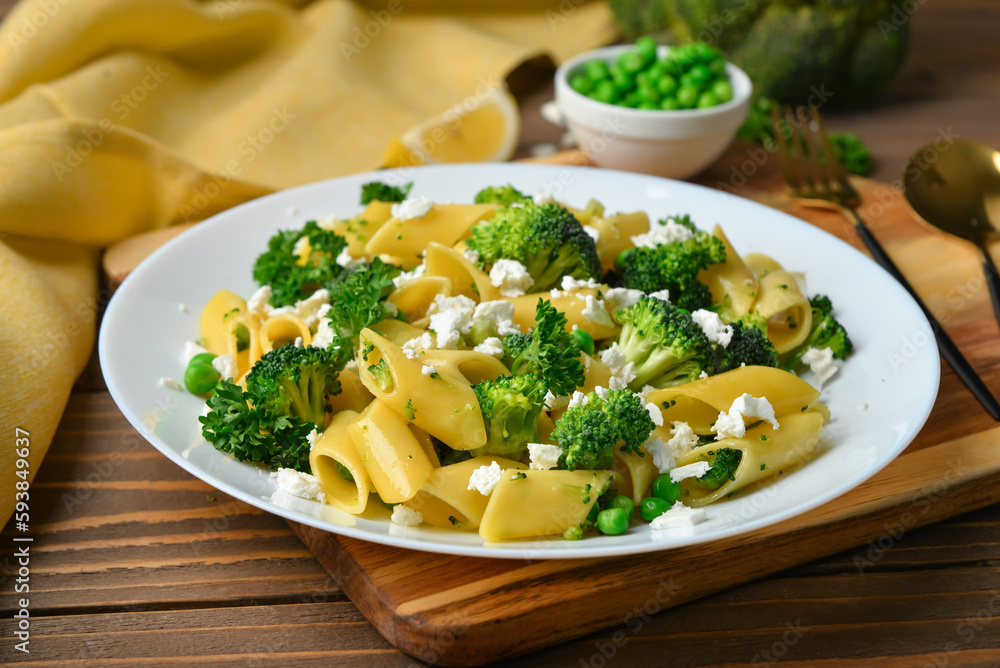 Plate with tasty penne pasta and broccoli on wooden background Plate with tasty penne pasta and broccoli on wooden background