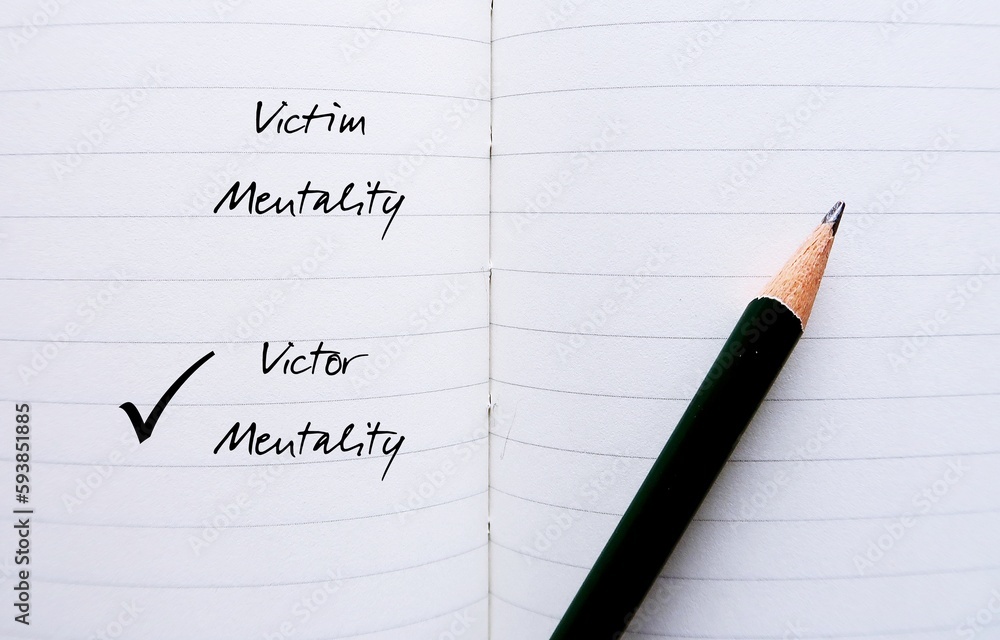 Notebook with pencil writing VICTIM and VICTOR MENTALITY, to overcome feeling like have no control over things and start developing growth mindset or positive attitude to improve position Notebook with pencil writing VICTIM and VICTOR MENTALITY, to overcome feeling like have no control over things and start developing growth mindset or positive attitude to improve position