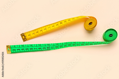 Orange and green measuring tapes on beige background