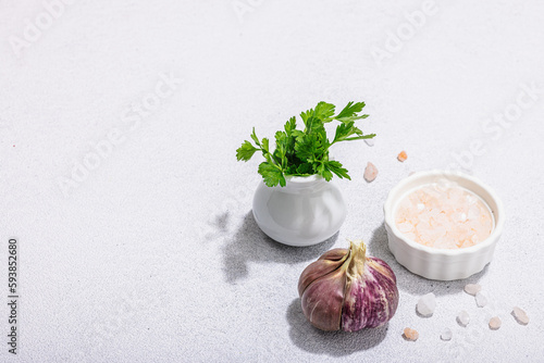 Kitchen cooking background with fresh parsley, garlic and sea salt. Hard light, dark shadow