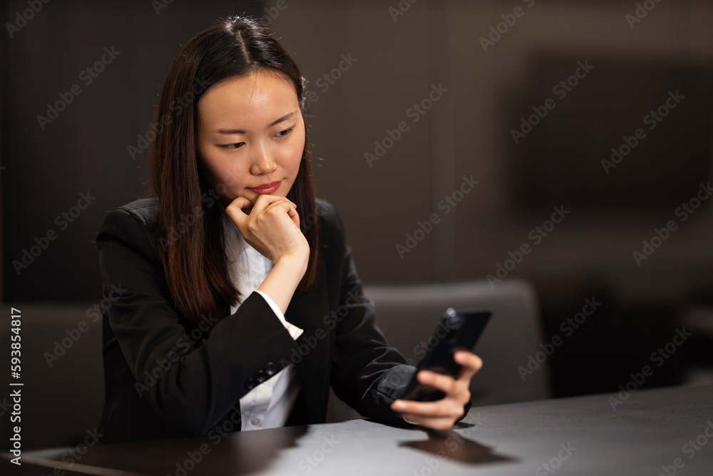 A shot of an elegant Chinese businesswoman using her smartphone in the conference room. A shot of an elegant Chinese businesswoman using her smartphone in the conference room.