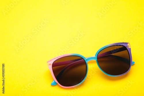 Colorful sunglasses on yellow background. Top view