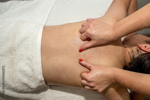 young caucasian woman lying face down getting relax full body massage at spa