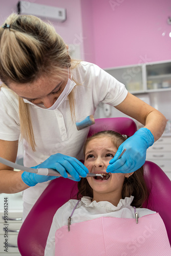 girl with her mouth open looking at  dentist while the doctor checks the child s teeth.