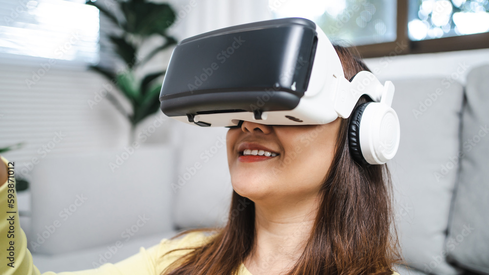 Young Asian woman gamer wearing virtual reality touching air during the VR experience Future home technology player hobby playful enjoyment concept. Young Asian woman gamer wearing virtual reality touching air during the VR experience Future home technology player hobby playful enjoyment concept.