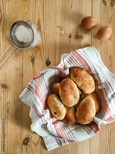 Above view of delicious fresh baked apple pies in a basket on a wood table, eggs and wheat flour.