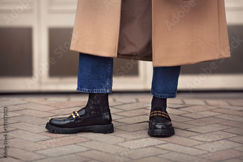 Close up female legs in jeans, stylish black loafers shoes and socks, street style fashion