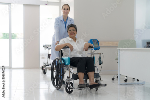 Doctor helping senior patient push wheelchair.
