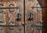 old wooden door with decorative wrought iron bolts and knockers and with a modern padlock