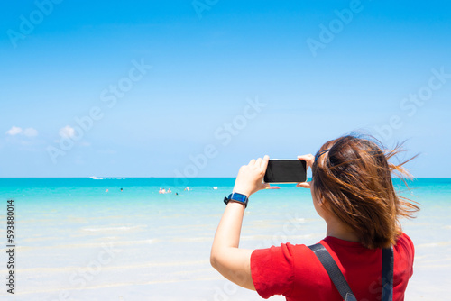 female tourist Taking pictures of the sea with a smartphone in the summer