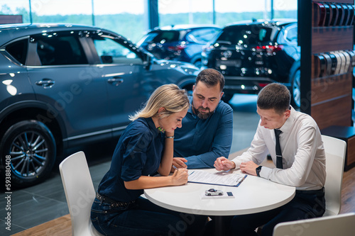 Happy caucasian couple signs a contract for the purchase of a car salon.