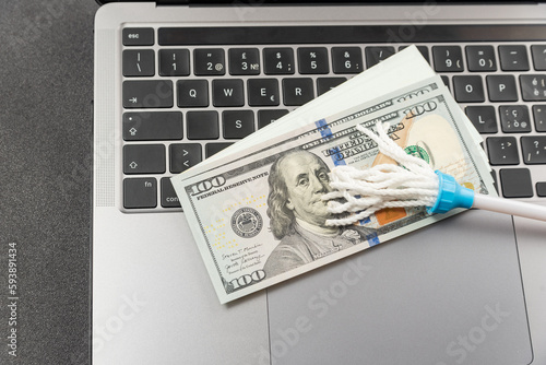 Toy mop and cash dollars on laptop keyboard. Concept of money laundering via the Internet. Online cleaning services.