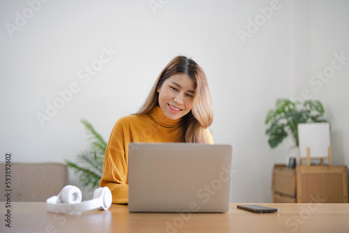 Asian business woman using headphone and laptop video conference meeting online work at home.