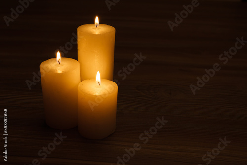 three burning candles in the semi-darkness