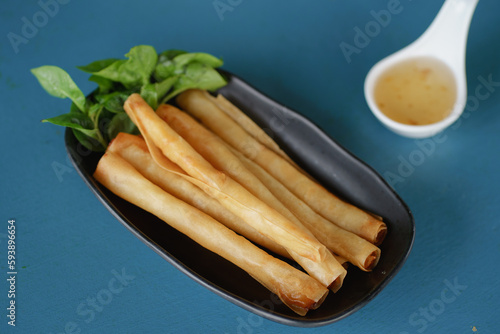 Ebiroll , Delicious fried raw shrimp spring roll with sweet sauce on blue table. snack food.