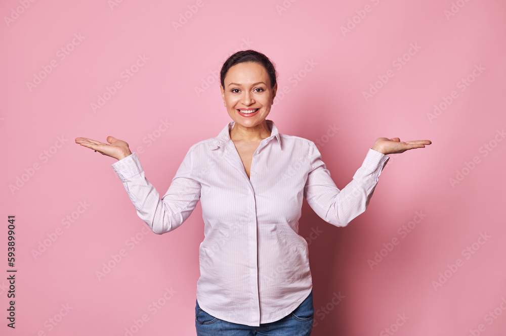 Happy smiling pregnant woman looking at camera, holding imaginary copy space on her hands palms up, on isolated pink background. Happy Mother's Day. Carefree pregnancy. Maternity and health concept Happy smiling pregnant woman looking at camera, holding imaginary copy space on her hands palms up, on isolated pink background. Happy Mother's Day. Carefree pregnancy. Maternity and health concept