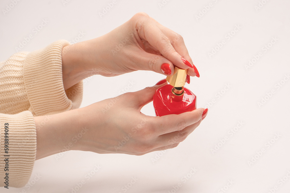 Red bottle of perfume in woman hand with red nails isolated on a white background. Red bottle of perfume in woman hand with red nails isolated on a white background.