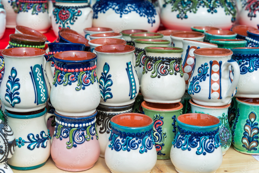 Traditional romanian handmade ceramic pottery mugs with rustic authentic decoration paintings on display.