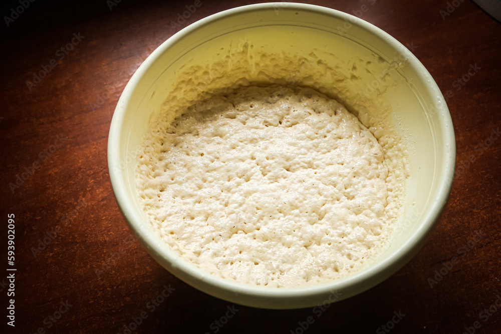 the process of cooking cooking dough in a yellow toe on a dark wooden table.