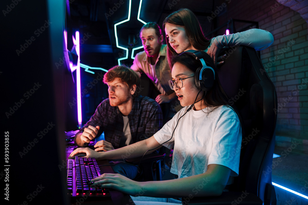 © Drobot Dean - Group of people watching their friend playing video game in cybersport club