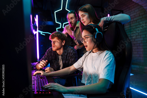 Group of people watching their friend playing video game in cybersport club