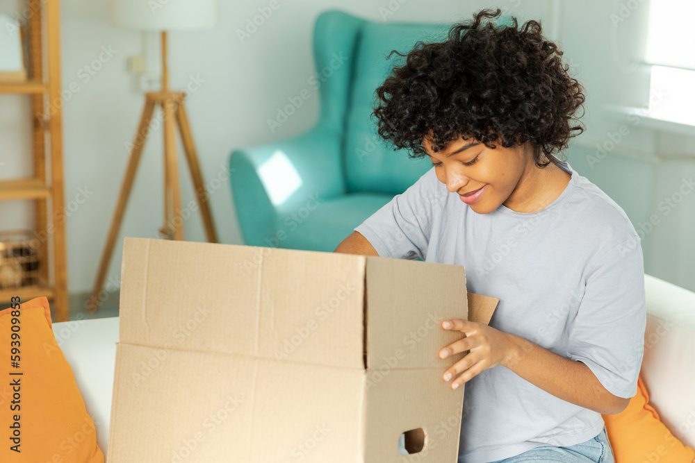 African girl unpacking delivery looking in box. Happy woman opening carton box. Female getting parcel looking at delivered goods items. Satisfied client positive feedback quick express deliver African girl unpacking delivery looking in box. Happy woman opening carton box. Female getting parcel looking at delivered goods items. Satisfied client positive feedback quick express deliver