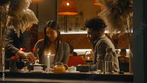 Fotografía African american man and asian woman sit in modern gastro cafe together