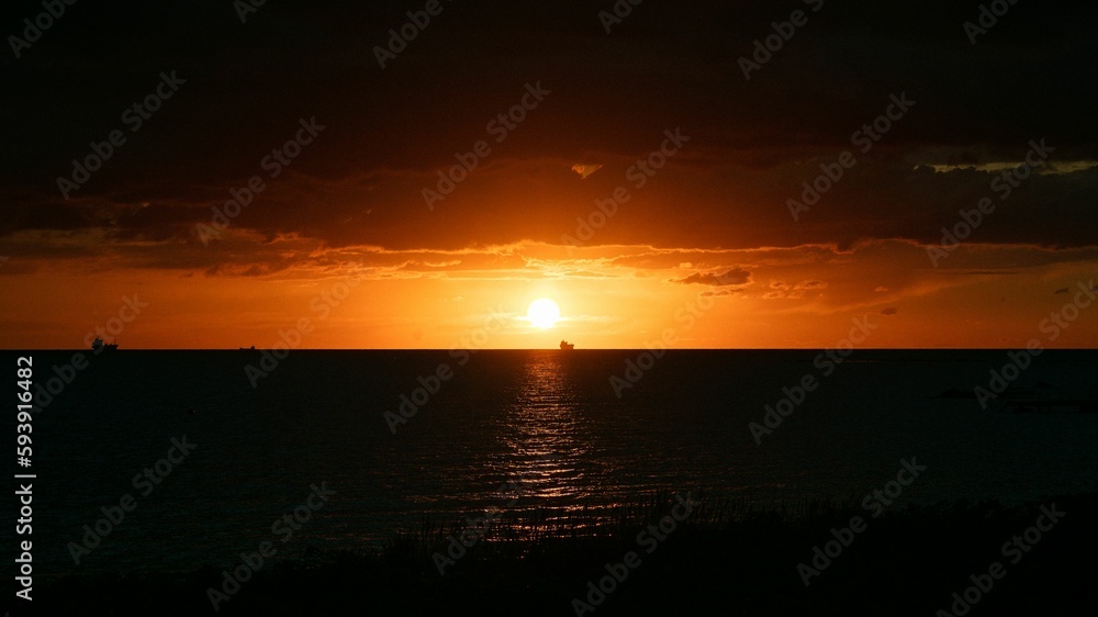 Golden sunset at sea under a dark sky