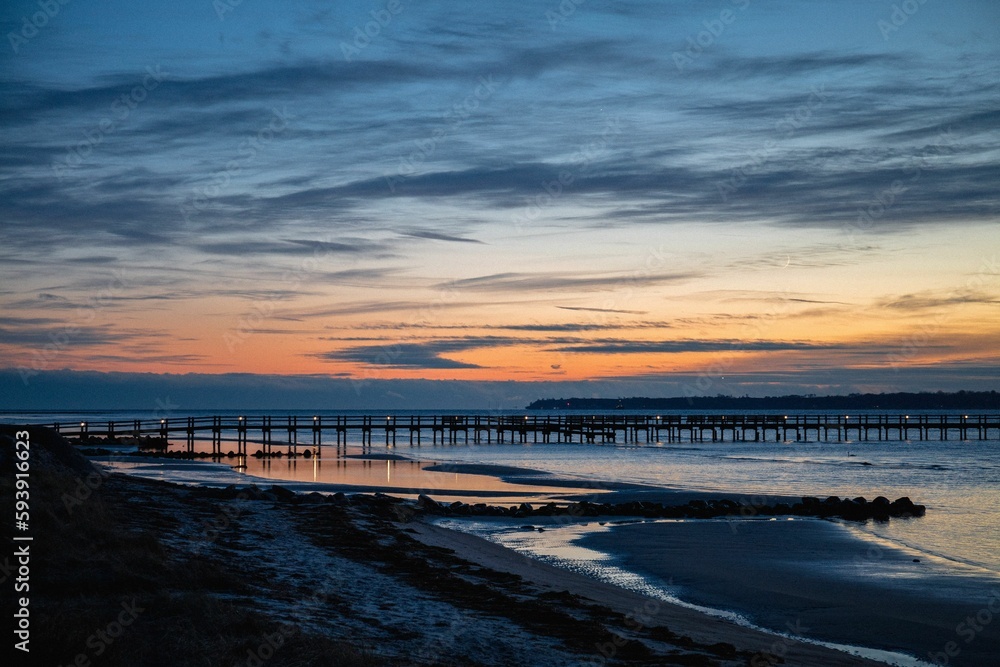 Long pier at sea against a sunset sky