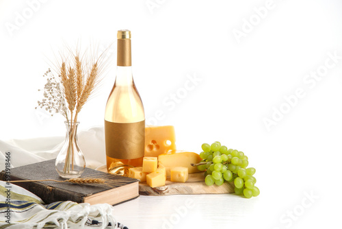 The concept of the Israeli holiday Shavuot. Bottle of wine, cheese slices and grapes on a wooden board, tallit, torah.