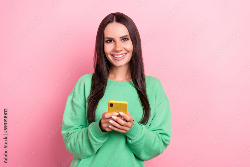 Photo of charming smiling good mood brunette hair lady wear green pullover hold phone review her new apple gadget isolated on pink color background Photo of charming smiling good mood brunette hair lady wear green pullover hold phone review her new apple gadget isolated on pink color background