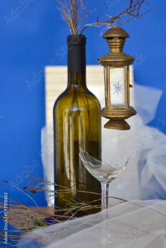 oil lamp hanging on a wine of bottle  and a mirror behind  and decoration a blue background 