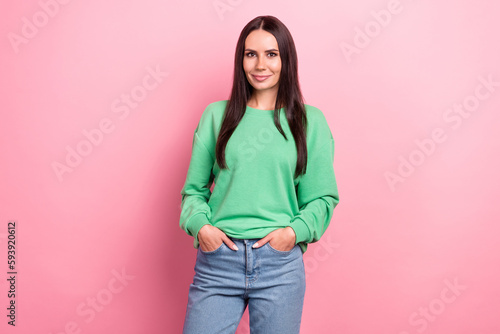 Portrait of pretty lovely girlish person long hairstyle wear green pullover holding palms in pockets isolated on pink color background