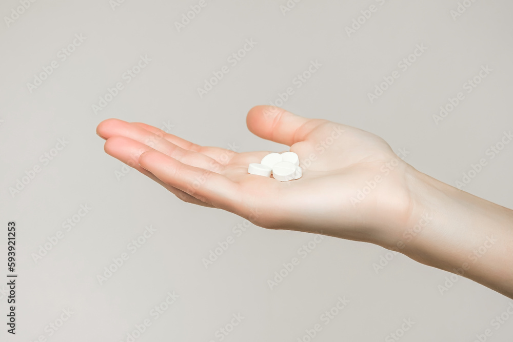 a woman holds a handful of white round pills in her palm a woman holds a handful of white round pills in her palm