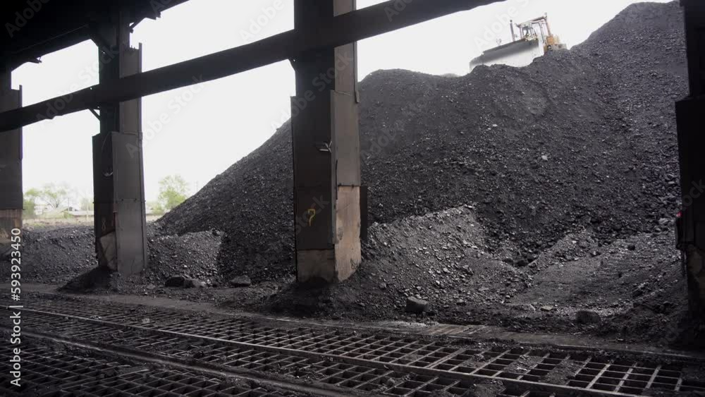 Almaty, Kazakhstan - 04.17.2023 : The tractor collects and unloads piles of coal at the heating plant. Almaty, Kazakhstan - 04.17.2023 : The tractor collects and unloads piles of coal at the heating plant.