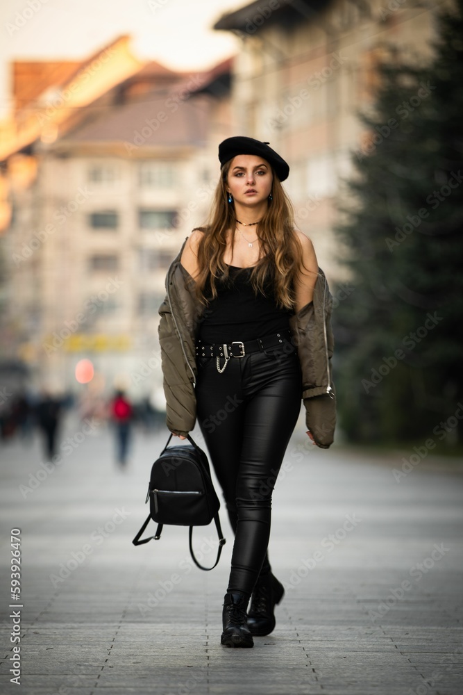 Vertical shot of a Caucasian woman wearing a casual outfit and a beret posing outdoors