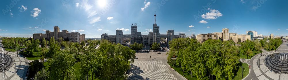 Aerial view on Derzhprom and Karazin National University buildings on Freedom Square with circle fountain, spring greenery and blue sunny sky in Kharkiv, Ukraine