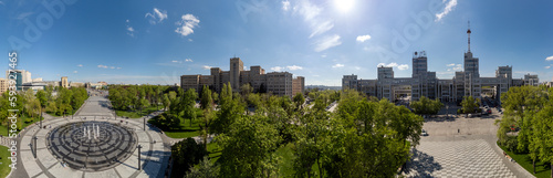 Aerial panorama on Derzhprom and main Karazin National University buildings on Freedom Square with circle fountain, spring greenery and blue sky in Kharkiv, Ukraine