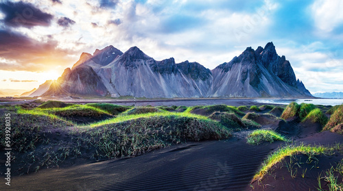 Scenic landscape with most beautiful mountains Vestrahorn on the Stokksnes peninsula and cozy lagoon with green grass on the sand dunes at sunset in Iceland. Exotic countries. Amazing places.