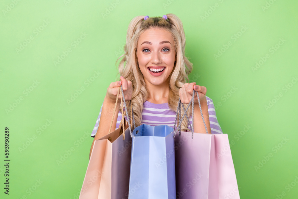 Photo of positive pleasant gorgeous girl with curly hairdo wear striped t-shirt holding new outfit isolated on green color background Photo of positive pleasant gorgeous girl with curly hairdo wear striped t-shirt holding new outfit isolated on green color background