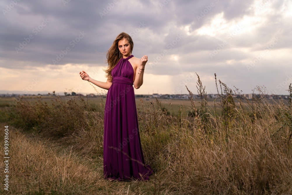 Obraz premium Caucasian blonde woman wearing a purple dress posing in a wild nature