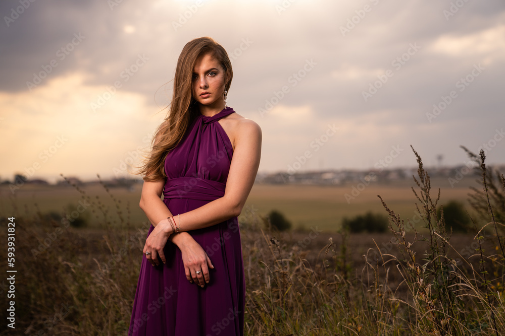 Caucasian blonde woman wearing a purple dress posing in a wild nature Caucasian blonde woman wearing a purple dress posing in a wild nature